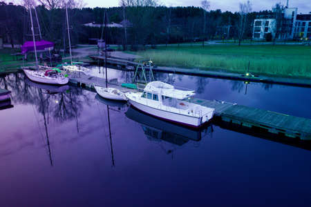Aerial drone top view photo of small motor boat or yacht standing near the wooden pier in the river or lake.のeditorial素材