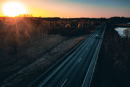Long country road with white lines down the centre stretching off past a lone tree to the distant horizonの写真素材
