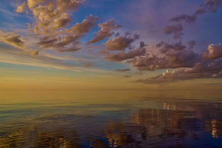 Beautiful sunset over sea with reflection in water, majestic clouds in the sky.の写真素材