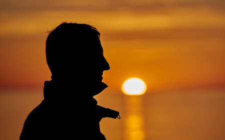man silhouette standing on sea sunset.