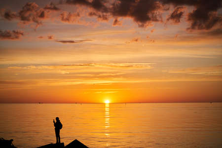 Woman or man standing on rock looking straight. Nature and beauty concept. Orange sundown. Girl...