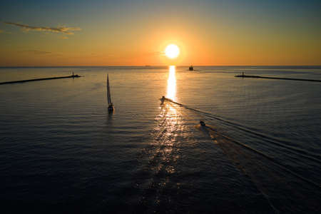Riga, Latvia 12-06-2021 Yacht sailing against sunset. Holiday lifestyle landscape with skyline sailboat. Yachting tourism - maritime evening walk. Romantic trip on luxury yacht during the sea sunset.のeditorial素材