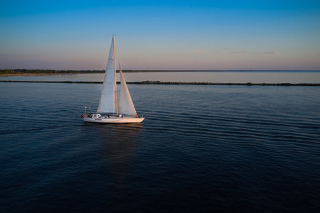 Riga, Latvia 12-06-2021 Yacht sailing against sunset. Holiday lifestyle landscape with skyline sailboat. Yachting tourism - maritime evening walk. Romantic trip on luxury yacht during the sea sunset.のeditorial素材