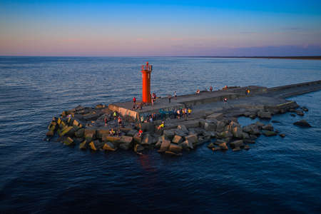 Amazing sunset sky and long stone pier with lighthouse.のeditorial素材