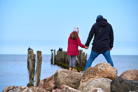 Back view of a young couple holding hands and looking at the seaの写真素材