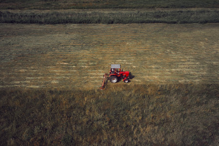 Tractor with hay mower cutting grass for hay on a fieldの写真素材