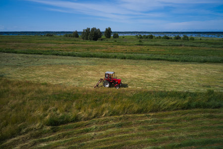 Aerial view of Tractor moving green field in summer Finlandの写真素材