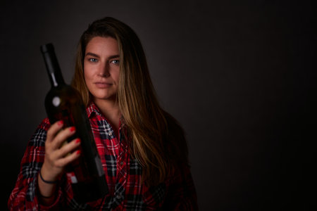 Young woman in a plaid shirt with a bottle of wine.の写真素材
