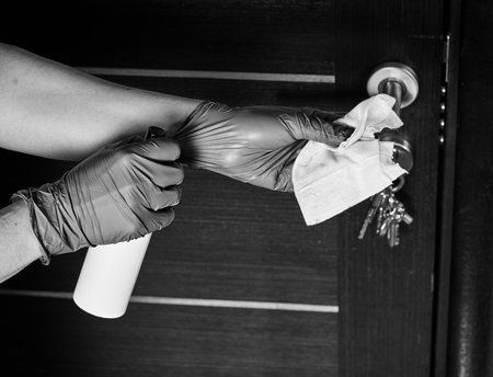 Hand cleaning metal door handle with paper tissue towel, closeup detail - coronavirus covid-19 spread prevention.の写真素材