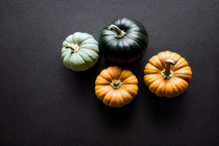 four small pumpkins are sitting on a black surface. .の写真素材