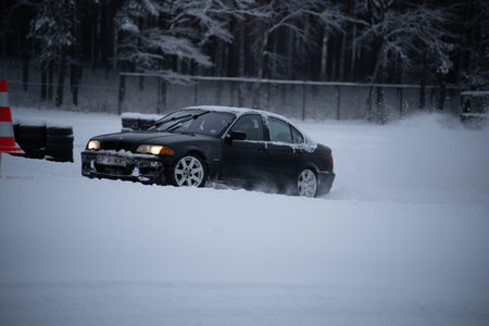 12-12-2022 Riga, Latvia a car driving through a snow covered parking lot in the snow with a red traffic cone in the background. .のeditorial素材