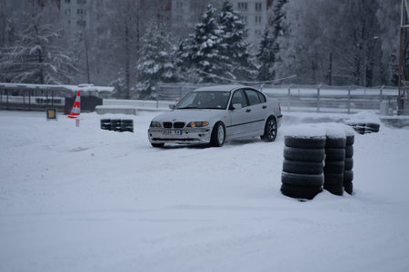 12-12-2022 Riga, Latvia a white car parked in a parking lot covered in snow next to a red traffic sign and a red traffic cone. .のeditorial素材