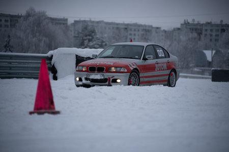 12-12-2022 Riga, Latvia a red car parked in the snow next to a red cone and a red traffic cone on a street. .のeditorial素材