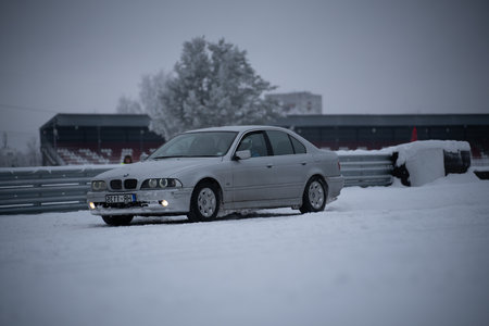 12-12-2022 Riga, Latvia a car parked in the snow near a fence and a building in the background with a fence and a building in the background. .のeditorial素材