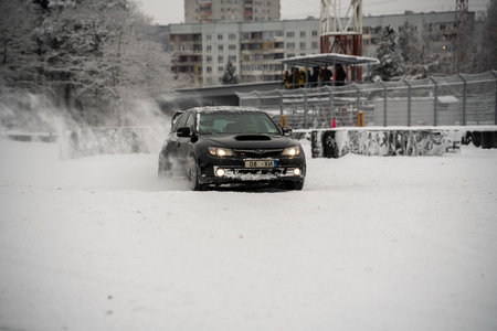 12-12-2022 Riga, Latvia a car driving through a snow covered street in the city with buildings in the background and a traffic light. .のeditorial素材