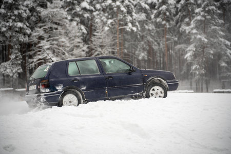 12-12-2022 Riga, Latvia a blue car is parked in the snow near trees and snow covered ground with snow on the ground and trees in the background. .のeditorial素材