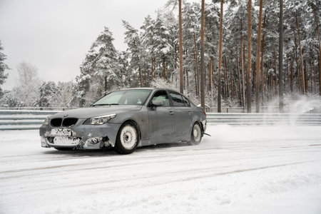 12-12-2022 Riga, Latvia a car driving on a snowy road near a forest with trees in the background and snow on the ground. .のeditorial素材