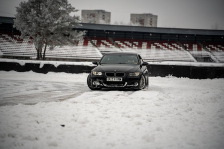 12-12-2022 Riga, Latvia a black car parked in the snow near a stadium bleachers and trees with snow on the ground. .のeditorial素材