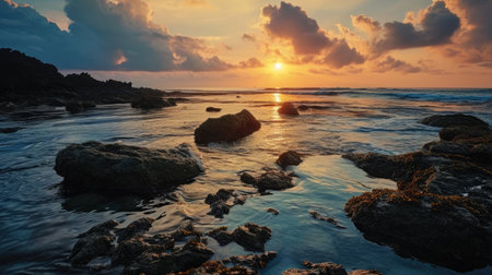 Sunset over the sea with rocks and stones in the foreground.の素材