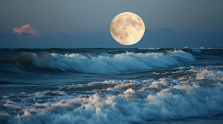 Full moon rising over the ocean at sunset with waves breaking on shoreの素材