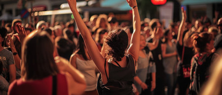 Rear view of a woman raising her arms during a music festivalの素材