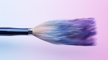Close-up of a paintbrush with blue paint on pink backgroundの素材