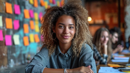 Portrait of smiling afro american businesswoman sitting in creative officeの素材
