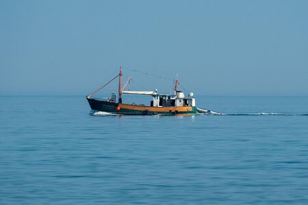 fishing boat on the baltic sea on a bright sunny day with clear skiesの写真素材