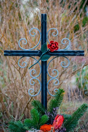 Friedhof Tegel, Berlin, Germany - november 29, 2018: Cast iron cross with a red rose on a graveの写真素材