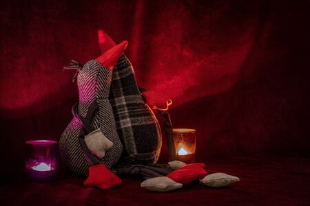 Romantic shot of two plush birds hugging each other on red velvet with two candlelightsの写真素材