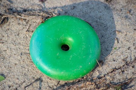 Abandoned toys - a childs green disk toy found as trash along a path in nature