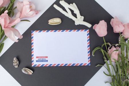 Flat lay composition with shells, coral, envelope and flowers. On envelope - inscription Air Mail in English, French and Spanish. Photo background. Top view with white and black paper. Nautical decorの写真素材