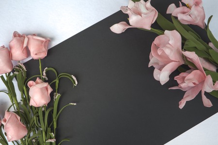Flat lay composition with blank place and flowers. Romantic photo background for love letters and wedding decor. Table top view with white and black paper. Floral decor mockupの写真素材