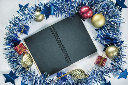 Vintage Christmas background with text place. Blue ribbon wreath. Red and golden fir tree ornament. Black paper notebook with blank page. Trendy Christmas backdrop for greeting message. Christmas flatの写真素材