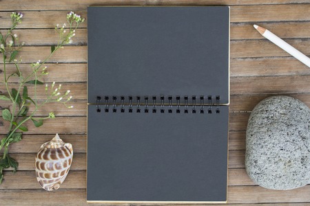 Black paper notebook on rustic wooden background with natural decor. Black notepad with blank page....