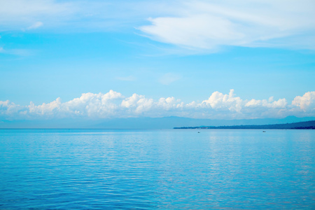 Tropical seascape with distant island and blue sky. Relaxing sea view with still seawater. Seaside...