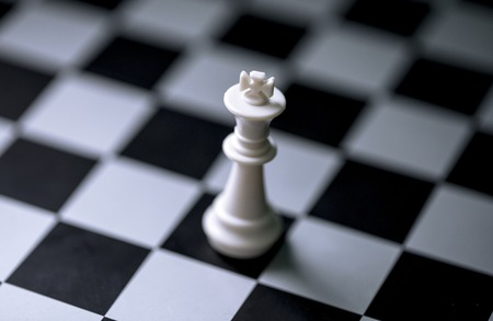 White king on chess board. Chess game figure on checkered board. White king alone on chessboard. Mate situation in chess rules. Business advantage or strong leadership concept. Chess king closeupの写真素材