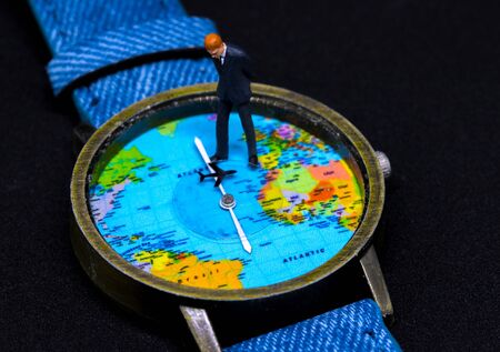 Businessman figurine on watch. World map clock. Worldwide business concept. Businessman macro photo....