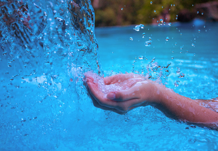 Woman hands and blue water. Fresh clean water current. Girl's hands in water flow. Hygiene concept photo. Calming moisture from natural water source. Clean ecology. Summer vacation. Swimming pool gameの写真素材