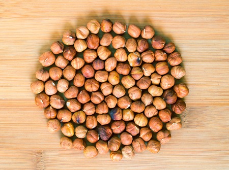 Hazelnut circle on wood background. Ripe hazel nut for food. Organic food rustic banner template with text space. Tasty healthy snack. Scattered hazel nut on table top view. Dry hazelnut pile flat layの写真素材