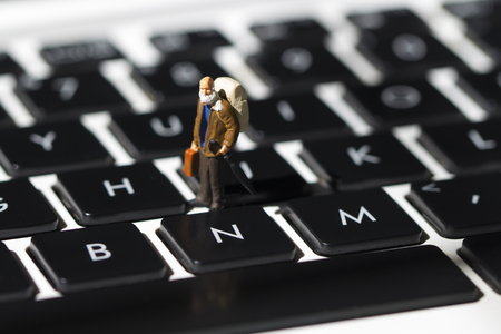 Tiny man and white notebook keyboard. Computer keyboard closeup with focus on N button. Press No. Internet browsing or programming. Old man computer education concept. Modern notebook keyboard closeupの写真素材