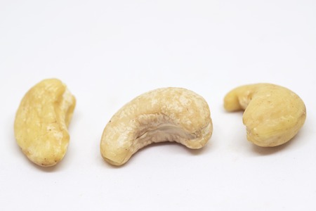 Cashew nut isolated on white background. Three ripe nut closeup photo. Simple organic food. Tasty healthy snack package design. Scattered cashew clipart. Cashew banner template with text placeの写真素材