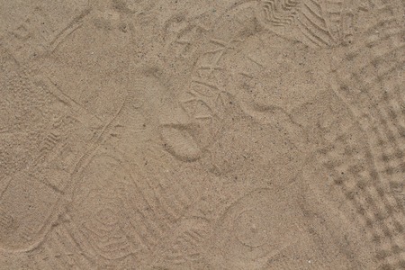 Yellow sand with foot marks photo texture. Shoe sole sand marks. Protecting feet on holiday. Many tourist shoe protectors background. Sand place with crowd step marks. Shoe imprints on sand roadの写真素材