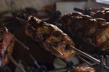Grilled chicken on skewer closeup photo. Roasted poultry closeup. Chicken grill process in local store of asian market. Traditional street food. Aromatic chicken barbecue. Summer outdoor food shopの写真素材