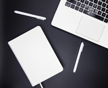 Work desk flat lay with white notebook keyboard and white pens and sketchbook. Everyday notebook or...