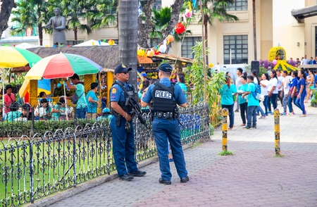 14 Nov 2018 - Cebu, the Philippines: two policemen protect the local festival. Ethnic people policemen. Filipino festival safety. Big city outdoor event. Harvest festival in park. Philippine fiestaのeditorial素材