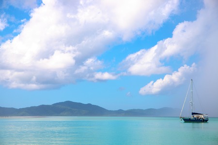 Sailing boat in turquoise blue sea under rain cloud. Beautiful tropical island landscape. Rain season weather in the Philippines. Cloudscape with sea view. Island hopping. Sailing in tropical sea.の写真素材