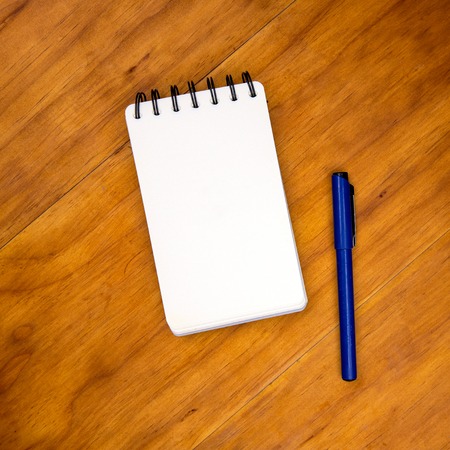 Blank page of notepad with pen on wooden table. Empty white paper notebook top view photo. Notebook...