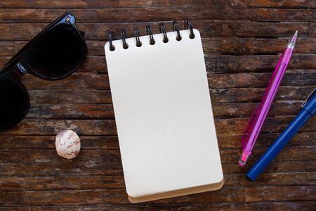 Spiral notepad blank page and pen on wooden background.