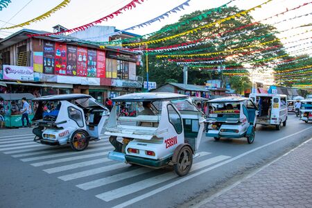 Puerto Princesa, Philippines - 28 Nov 2018: city landscape with tricycle and building. Filippino town traffic on busy street. Custom pedicab for passenger transportation. Travel in South Asiaのeditorial素材
